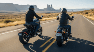 The Silent Rebellion: Can Electric Motorcycles Win the Soul of the American Biker? Two motorcyclists riding side-by-side on a scenic desert highway with large mesas in the background, showing the contrast between a modern and a classic motorcycle.