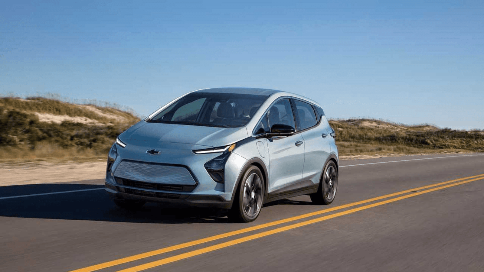 Chevrolet Bolt EUV Driving on a Coastal Highway – 2025 A light blue Chevrolet Bolt EUV driving along a sunny coastal highway, showcasing modern electric vehicle design and performance.