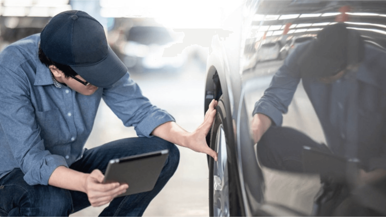 EV Buyer Inspecting Tire and Exterior During Used Electric Car Evaluation A buyer wearing a cap and holding a tablet carefully inspecting the tire and body of a used electric car in a parking garage during a pre-purchase evaluation.
