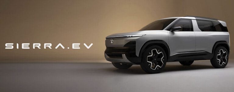 A studio promotional shot of the silver Tata Sierra.EV concept SUV, featuring a futuristic boxy design, black cladding, unique dual-tone alloy wheels, and the text 'SIERRA.EV' displayed prominently on the left.